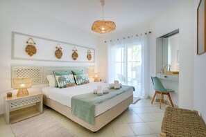 Ein Schlafzimmer mit einem Bett, Nachttischen, einem Schreibtisch, einem Sessel und einem großen Fenster.