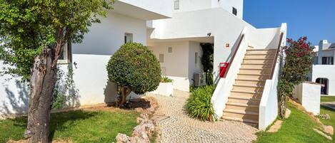 A white building with a cobblestone pathway leading to a staircase.