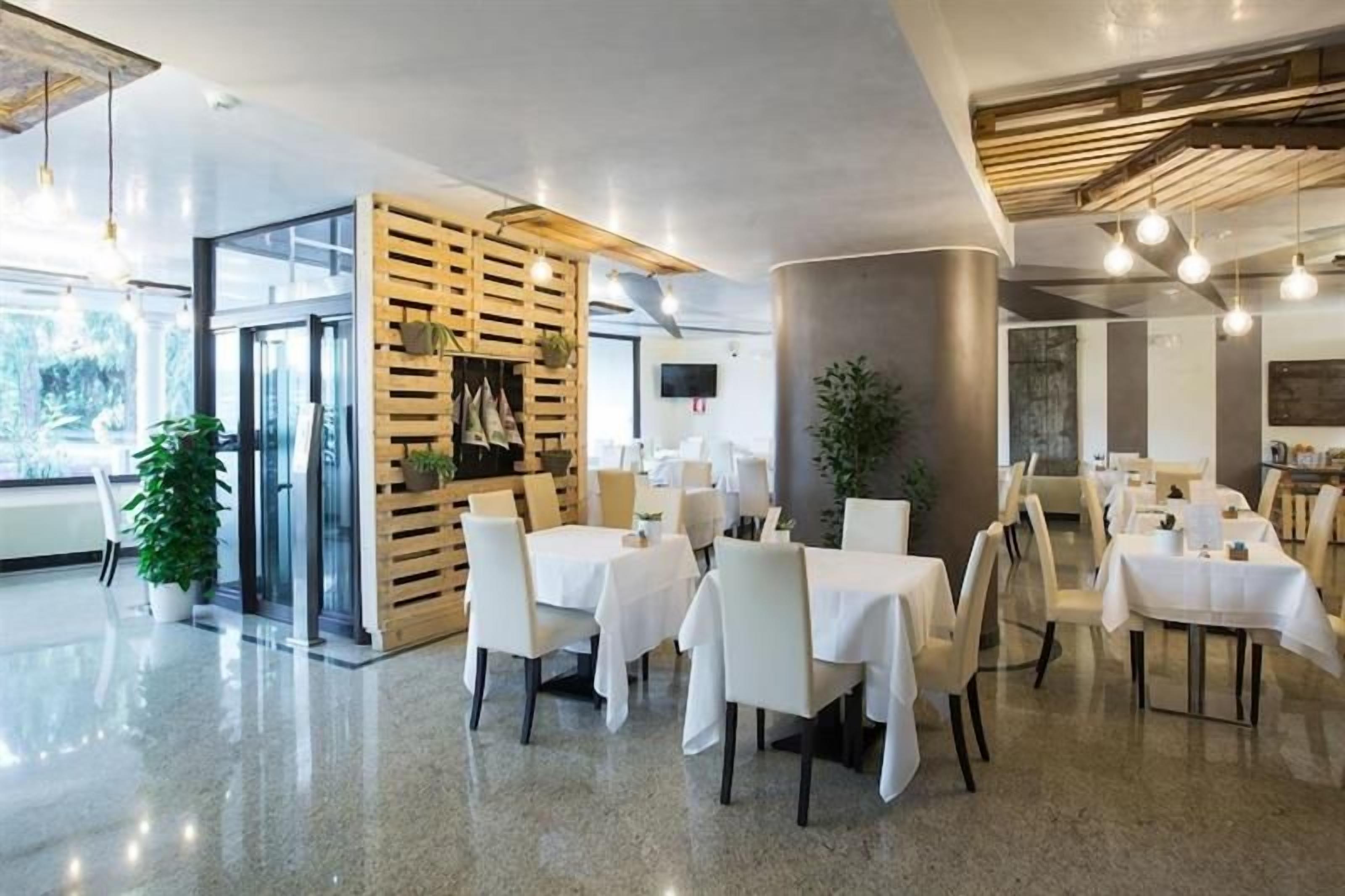 Un interno ristorante moderno con tavoli e sedie, una parete divisoria in legno e un'ampia finestra.
