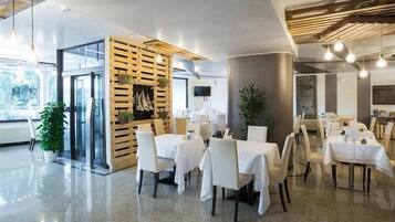 Un interno ristorante moderno con tavoli e sedie, una parete divisoria in legno e un'ampia finestra.