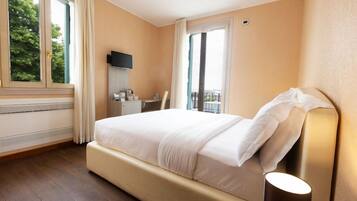 Una camera d'albergo con un letto grande, una TV a schermo piatto, un comodino e una finestra con tende.
