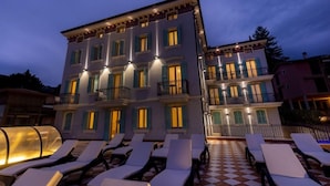 A multi-story hotel with balconies and a checkered outdoor seating area. - Mefuta Hotel (Gardone Riviera)