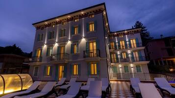 Un hotel a più piani con balconi e un'area salotto esterna con pavimento a scacchi.