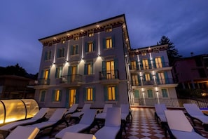 Ein mehrstöckiges Hotel mit Balkonen und einer Sitzgelegenheit im Freien mit Schachbrettmuster.