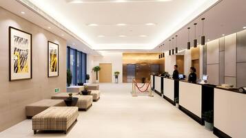 A hotel lobby with a reception desk, seating area, and a large window.