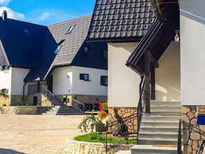 A modern building with a stone facade, a staircase leading to the entrance, and a well-maintained garden area. - Plivica Village Etno Garden (Plitvicka Jezera)