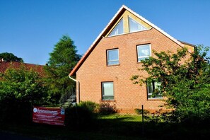 A two-story brick building with a sloped roof, a visible staircase, and a signboard in front. - Holiday apartment with 2 bedrooms (Neustadt)