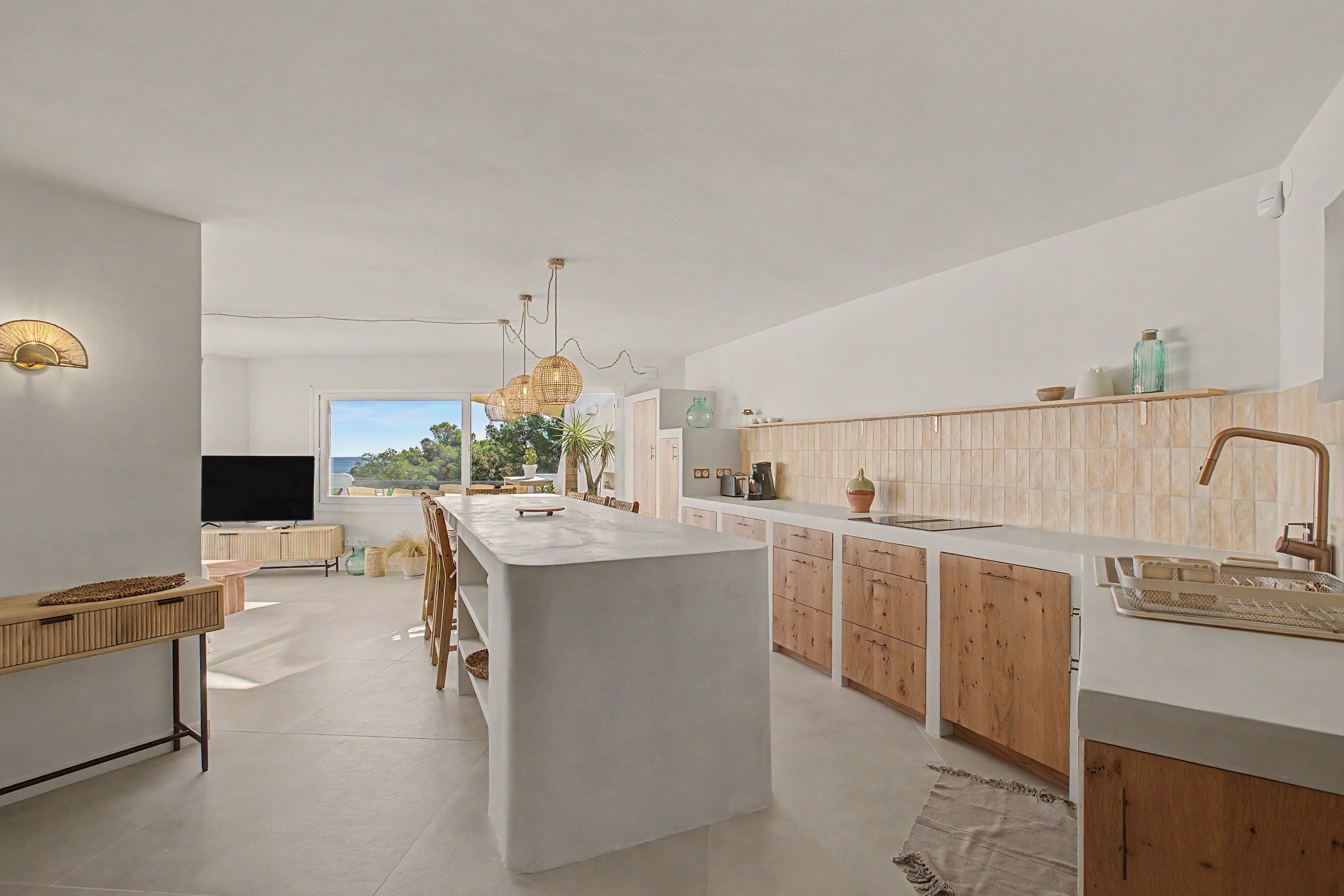 Una cocina moderna con una isla central, armarios de madera y un amplio ventanal con vistas a zonas verdes.
