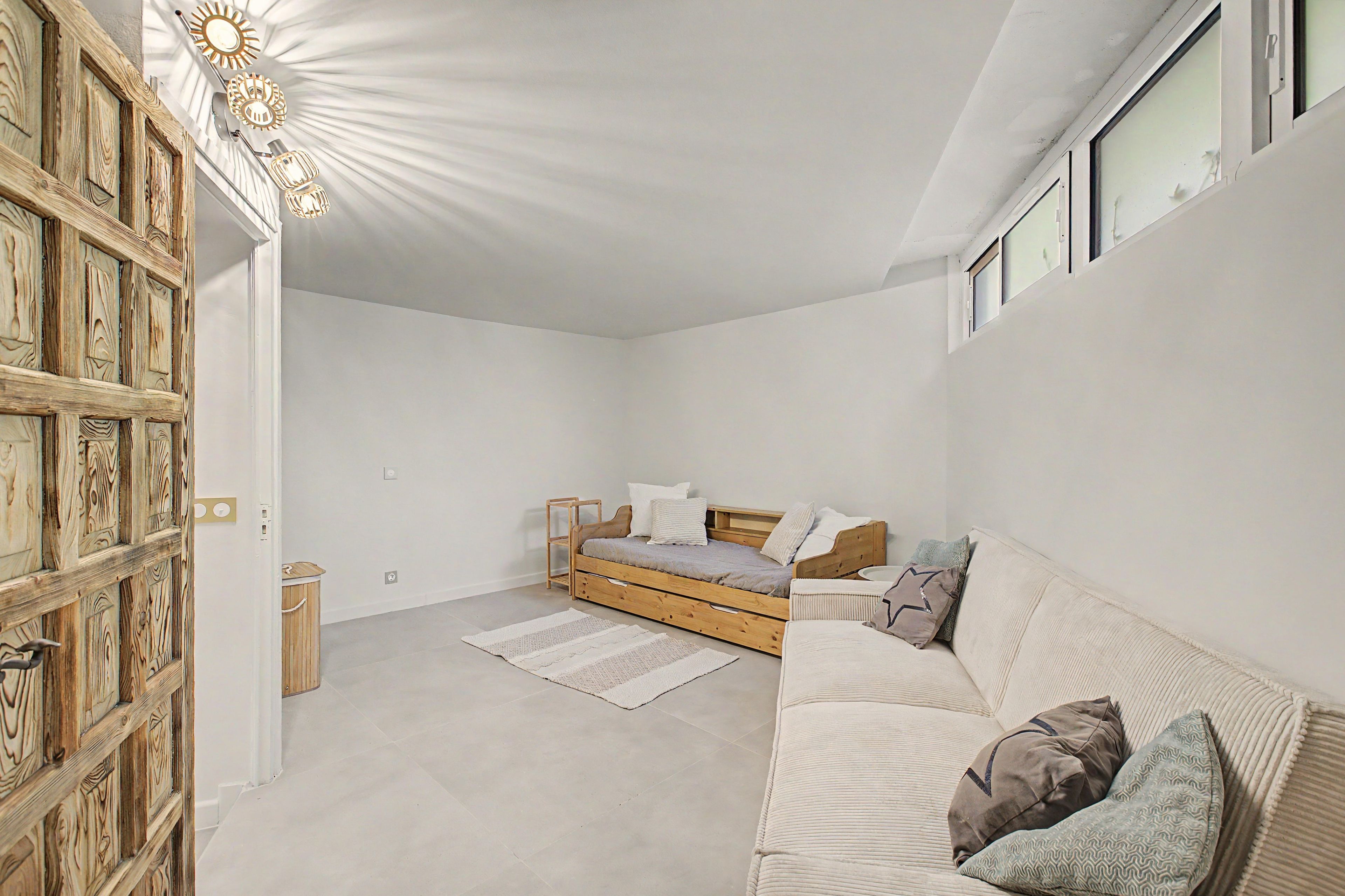 A bedroom with a wooden bed, a sofa, a small table, and a trash bin.
