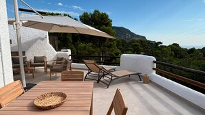 Een terras buiten met houten meubels, een tafel en een grote parasol.