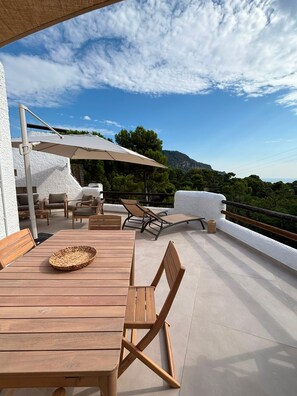 Une terrasse extérieure avec des meubles en bois, une table et un grand parasol.