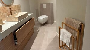 Een moderne badkamer met een wastafel, toilet en een handdoekhouder.