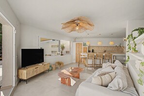 A modern living room with a flat-screen TV, a wooden coffee table, and a sofa with cushions.