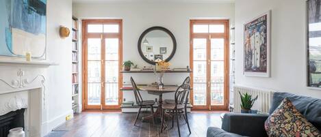 A living room with a fireplace, a dining area with a round table, and a sofa with a patterned cushion.