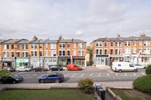 A street view with terraced houses, parked cars, and a white van. - Soulful 1BDR Flat with Balconies in Kentish Town (Greater London)