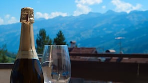 A bottle of Müller Thurgau wine and an empty glass on a balcony with a mountain view. - Fiemmea – Hidden Chalet, Valley View in Cavalese (Cavalese)
