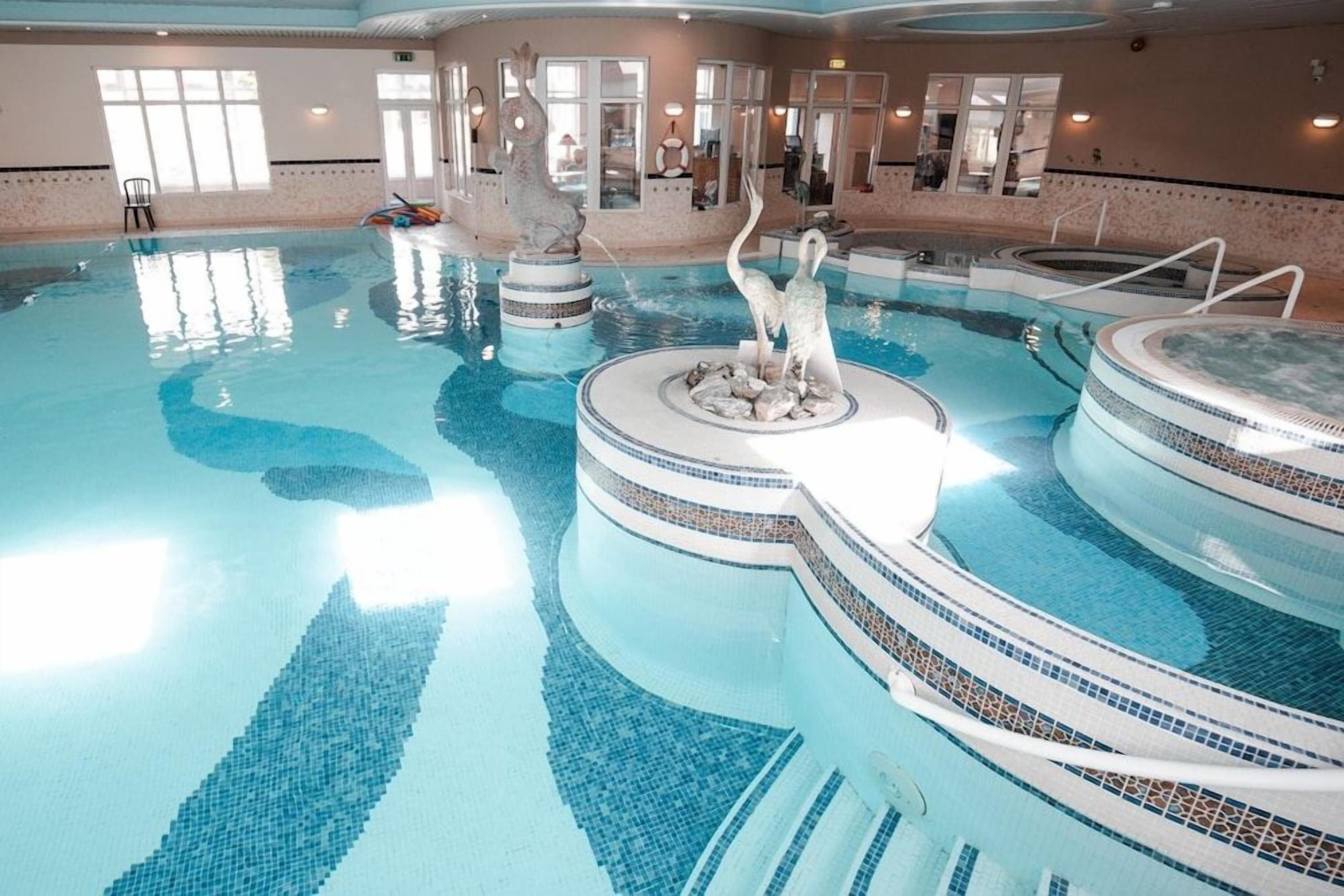 An indoor swimming pool with multiple levels and a central fountain.