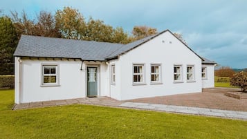 A single-story white building with a grey roof, a front door, and a small porch area.