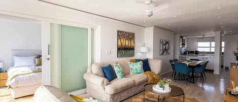 A modern living room with a sofa, coffee table, and a dining area with chairs.