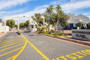 Un barrio residencial con un cartel que indica 'Woodbridge Island' y una entrada con portón.