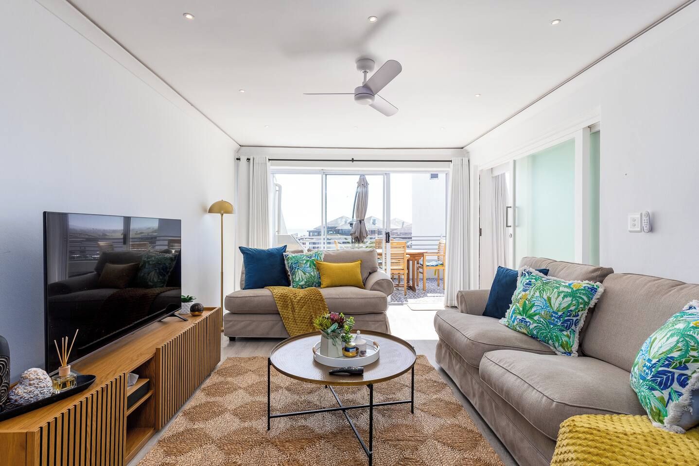Ein modernes Wohnzimmer mit Flachbildfernseher, zwei Sofas, einem Couchtisch und einem Deckenventilator.