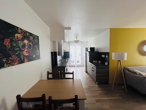 A modern kitchen with a dining area, a yellow accent wall, and a large painting on the wall.