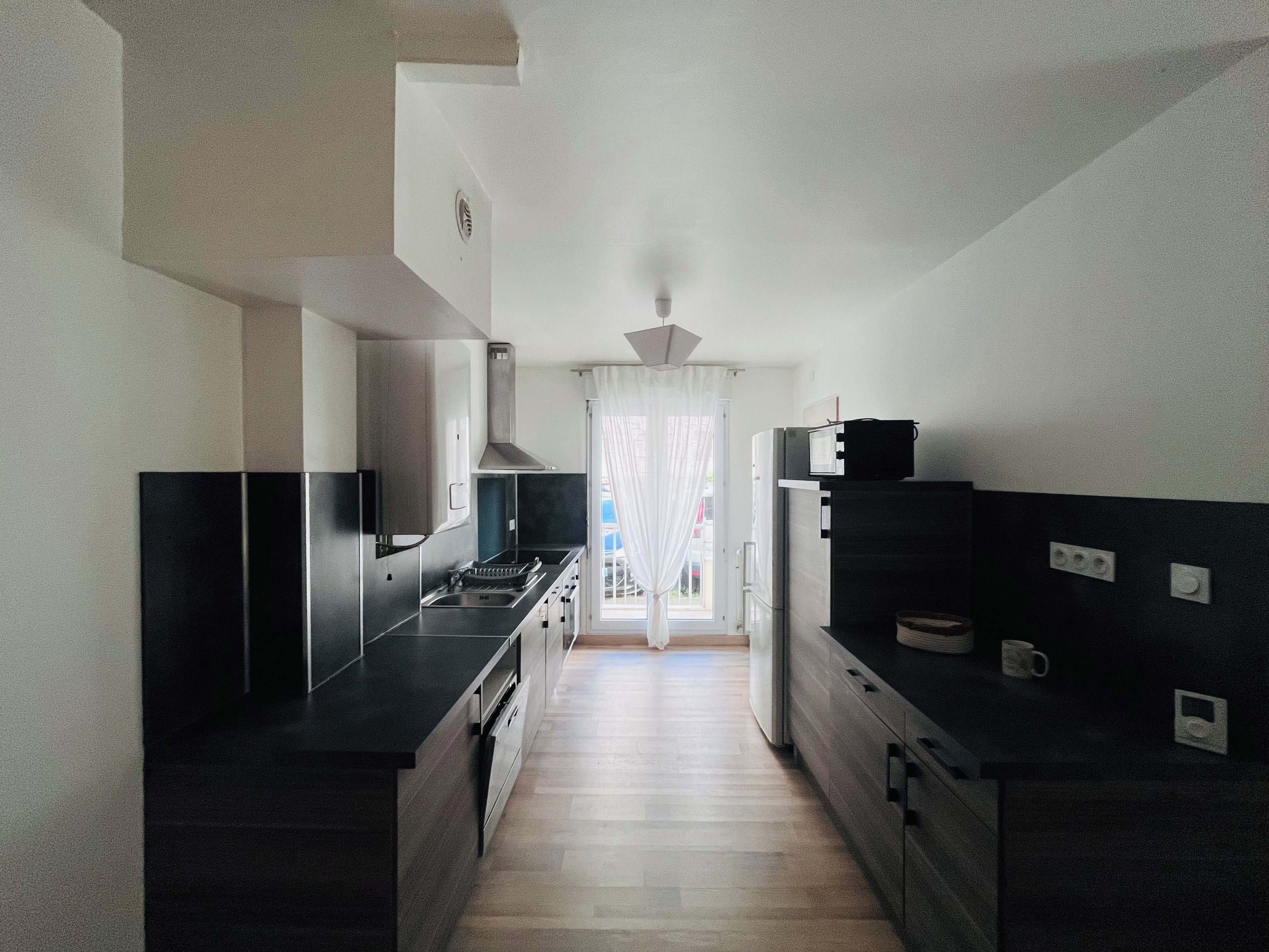 A modern kitchen with a central island, built-in appliances, and a view to the outside.