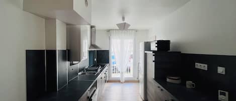 A modern kitchen with a central island, built-in appliances, and a view to the outside.