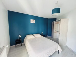 A bedroom with a bed, bedside tables, a wardrobe, and a blue wall.