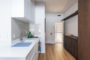 Een moderne keuken met witte kastjes, een roestvrijstalen spoelbak en een groene waterkoker.