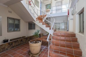 A multi-level interior with a central staircase, potted plants, and a fire alarm. - Kloof Street Studio Table Mountain views by ctha (Cape Town)