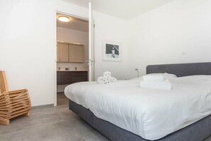 Ein Schlafzimmer mit einem Bett, einer Tür zu einem Badezimmer und einem Stapel Holzbretter.