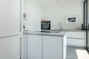 Eine moderne Küche mit weißen Schränken, einem eingebauten Ofen und einer Edelstahl-Arbeitsplatte.