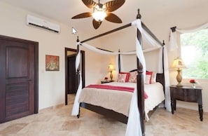 A four-poster bed with a canopy, a ceiling fan, and a nightstand with a lamp. - Red Frog Beach Island Resort And Spa (Bastimentos)