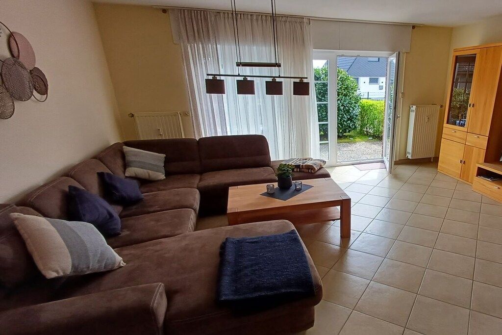 Ein Wohnzimmer mit Ecksofa, Couchtisch und einer Schiebetür zum Garten.
