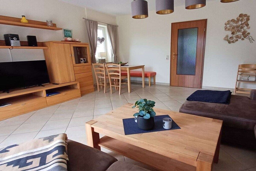 Ein Wohnzimmer mit Fernseher, Holzmöbeln, einem Essbereich und einer Tür mit Milchglasfenster.