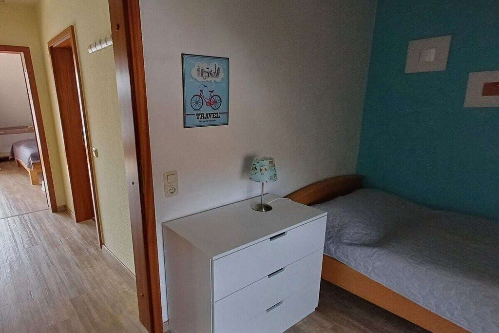 Ein Schlafzimmer mit einem Einzelbett, einem Nachttisch und einer Wandlampe.