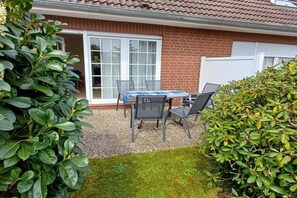 Een terras met een tafel, stoelen, een schuifpui en een bakstenen muur.