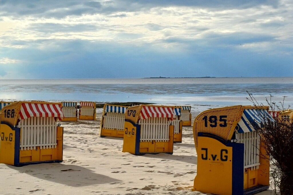 Beach huts numbered 168, 170, and 195 with 'JvG' on them, lined up on a sandy beach with the sea in the background.