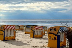 Beach huts numbered 168, 170, and 195 with 'JvG' on them, lined up on a sandy beach with the sea in the background. - House on Häfchenweg Apartment 6 (Cuxhaven)