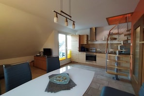 Eine moderne Küche mit Essbereich, einer Treppe und Blick ins Freie.