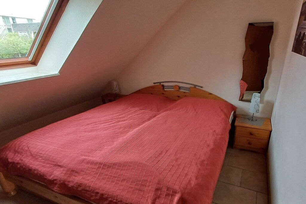 Une chambre à coucher avec un lit, une table de chevet, une lampe et une fenêtre.