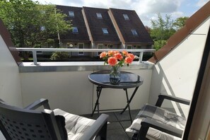 A balcony with a table, chairs, and a vase of flowers. - House on Häfchenweg Apartment 6 (Cuxhaven)