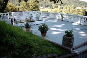 A rooftop terrace with a white lattice fence, potted plants, and a view of the surrounding landscape. - Jendrusiak holiday apartment (Krayenberggemeinde)