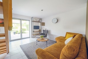A modern living room with a sofa, a coffee table, and a TV. - Holiday home at Embricana (Emmerich am Rhein)