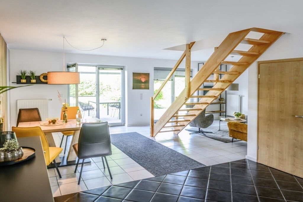 Ein modernes Interieur mit Essbereich, einer Treppe und Blick ins Freie.