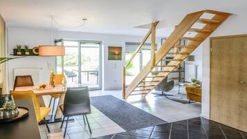 Ein modernes Interieur mit Essbereich, einer Treppe und Blick ins Freie.