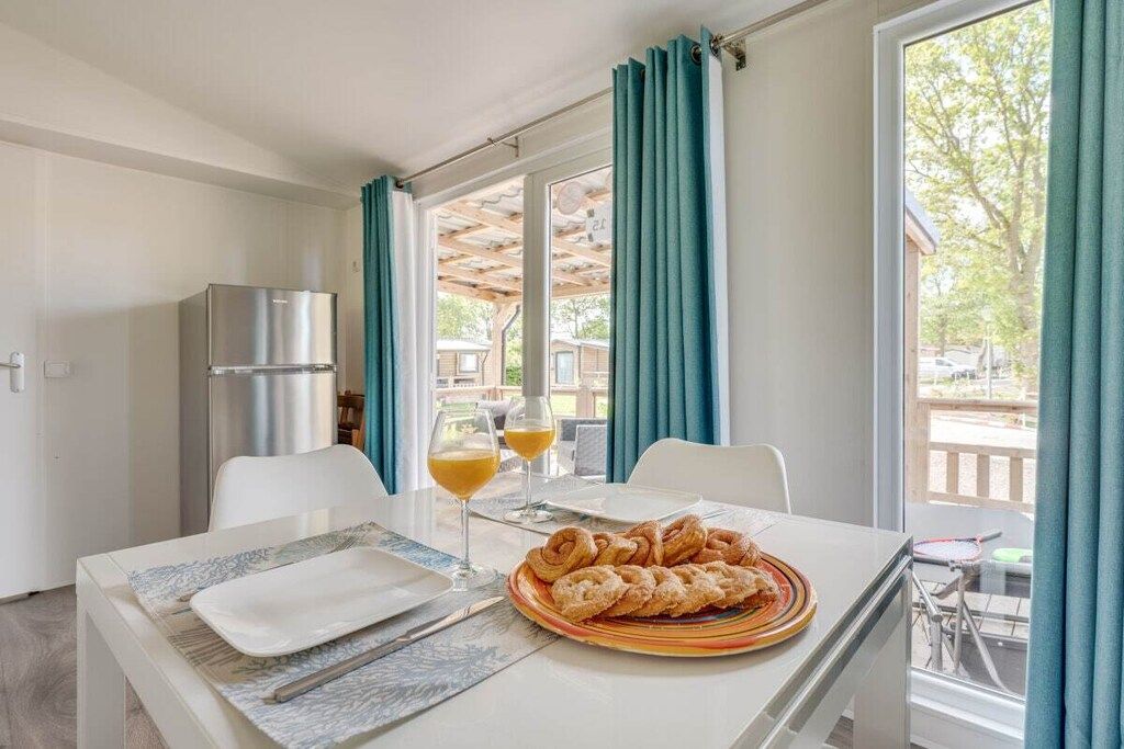 A dining area with a table set for two, a plate of pastries, and two glasses of orange juice.