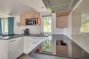 Una cocina moderna con microondas, cafetera y ventana.