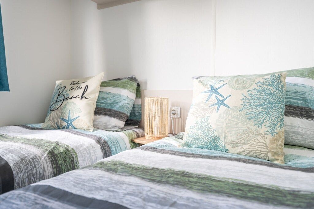 Een slaapkamer met twee bedden, elk voorzien van een gestreepte spreidek en passende kussens.